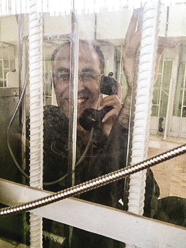 a man sitting in prison talking to someone on the phone and smiling