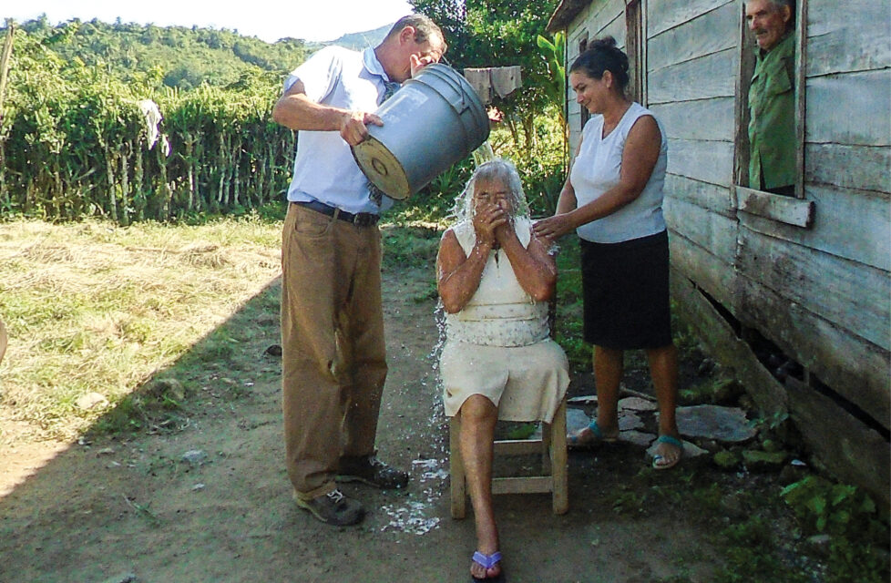Cuban Christians Launch Evangelism Campaign in Havana A man pours water over the head of a woman for baptism