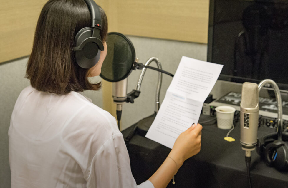 North Korean Government Listens in on Illegal Radio Programs Woman with headphones on reading a piece of paper into a microphone