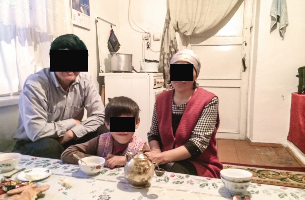 Believer Beaten Nightly for Three Years, Leads Abusers to Christ family of three sit in their kitchen with black boxes over their faces